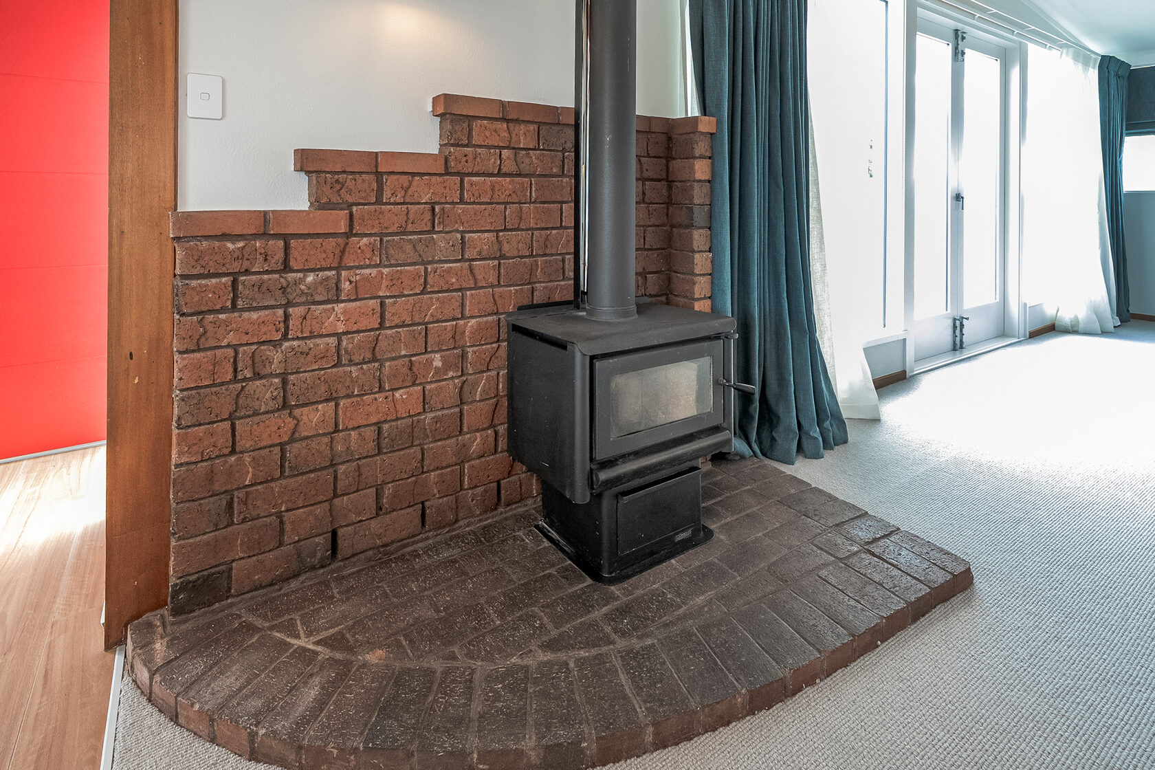 Freestanding wood-burning fireplace with brick surround and hearth in a cozy living room corner.