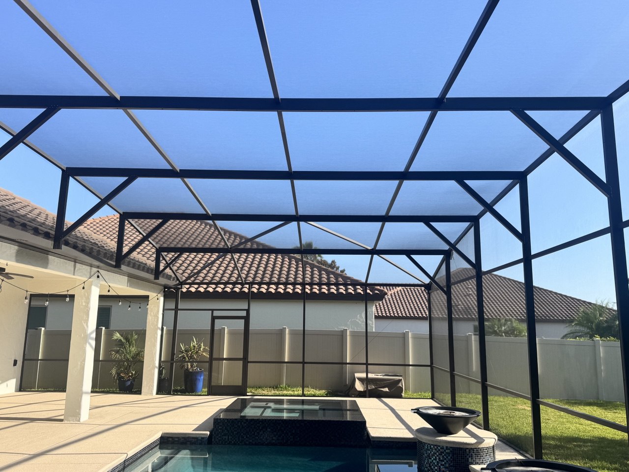 Freshly painted black pool cage with new screens over a pool in Orlando
