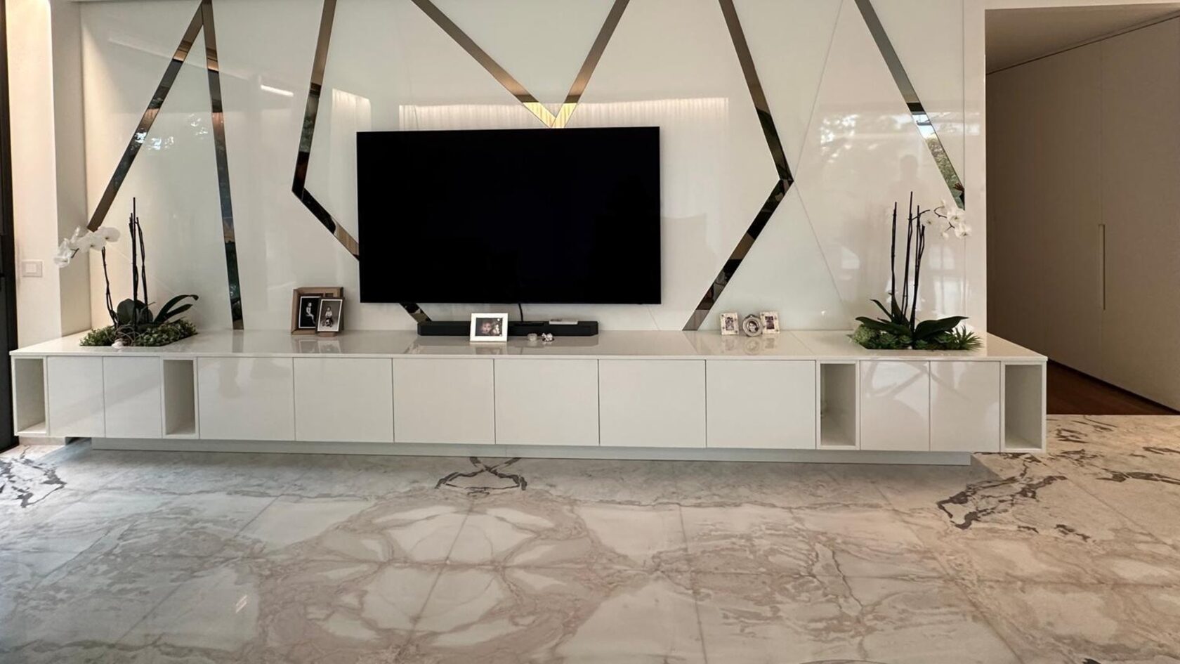 Casa Quadrelli: la parete attrezzata bianca con gli inserti a specchio e il pavimento in marmo.