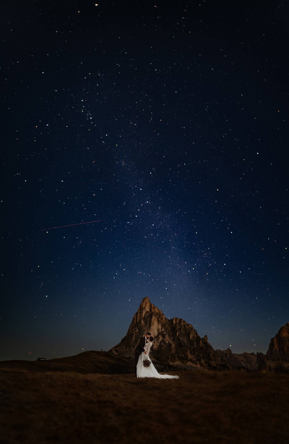 After‑wedding session in the Alps — bride and groom under a starry night sky with dramatic mountain backdrop.