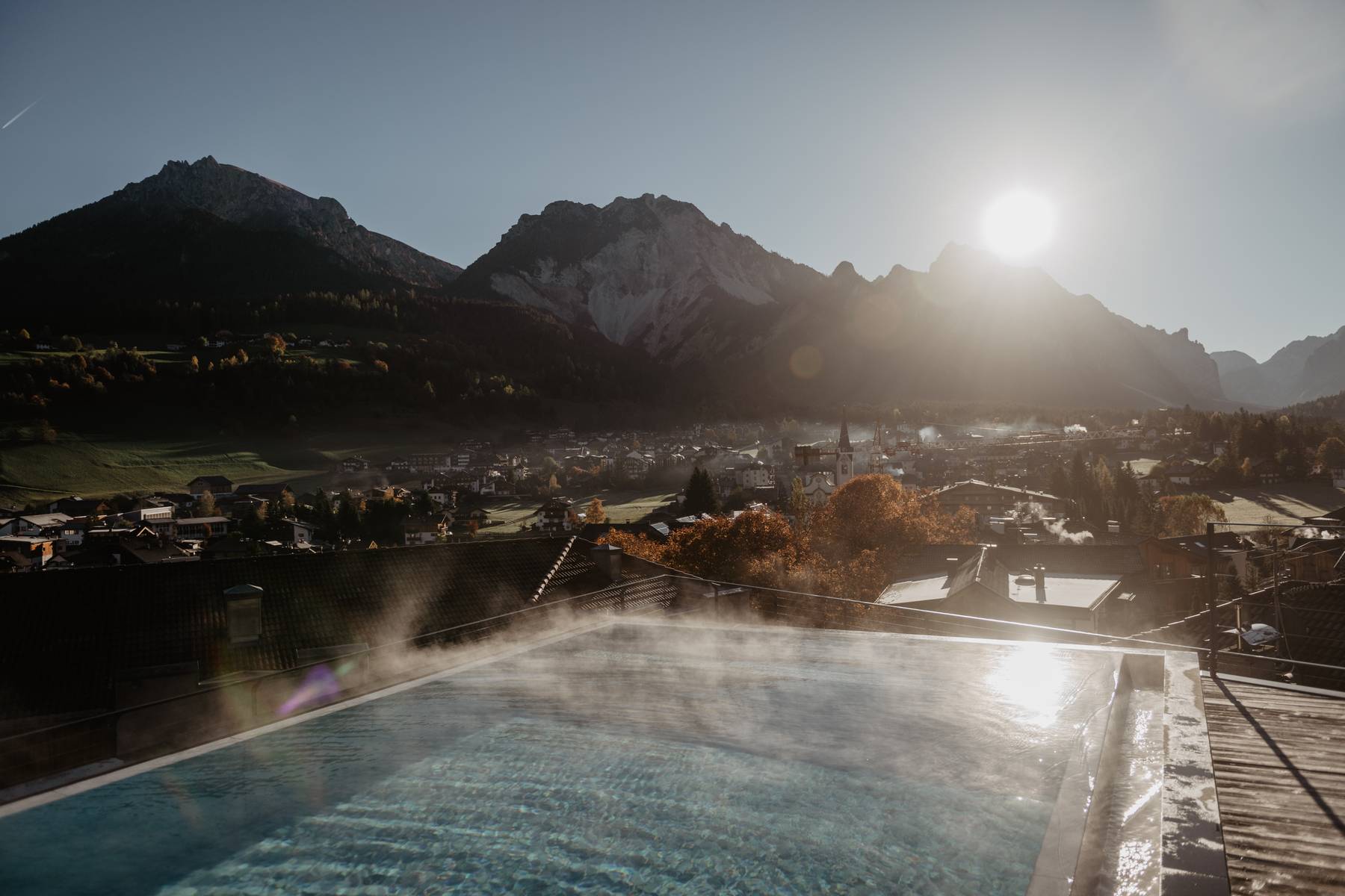 Heated outdoor pool at sunrise with a panoramic Dolomites mountain view, Italy, wellness getaway atmosphere