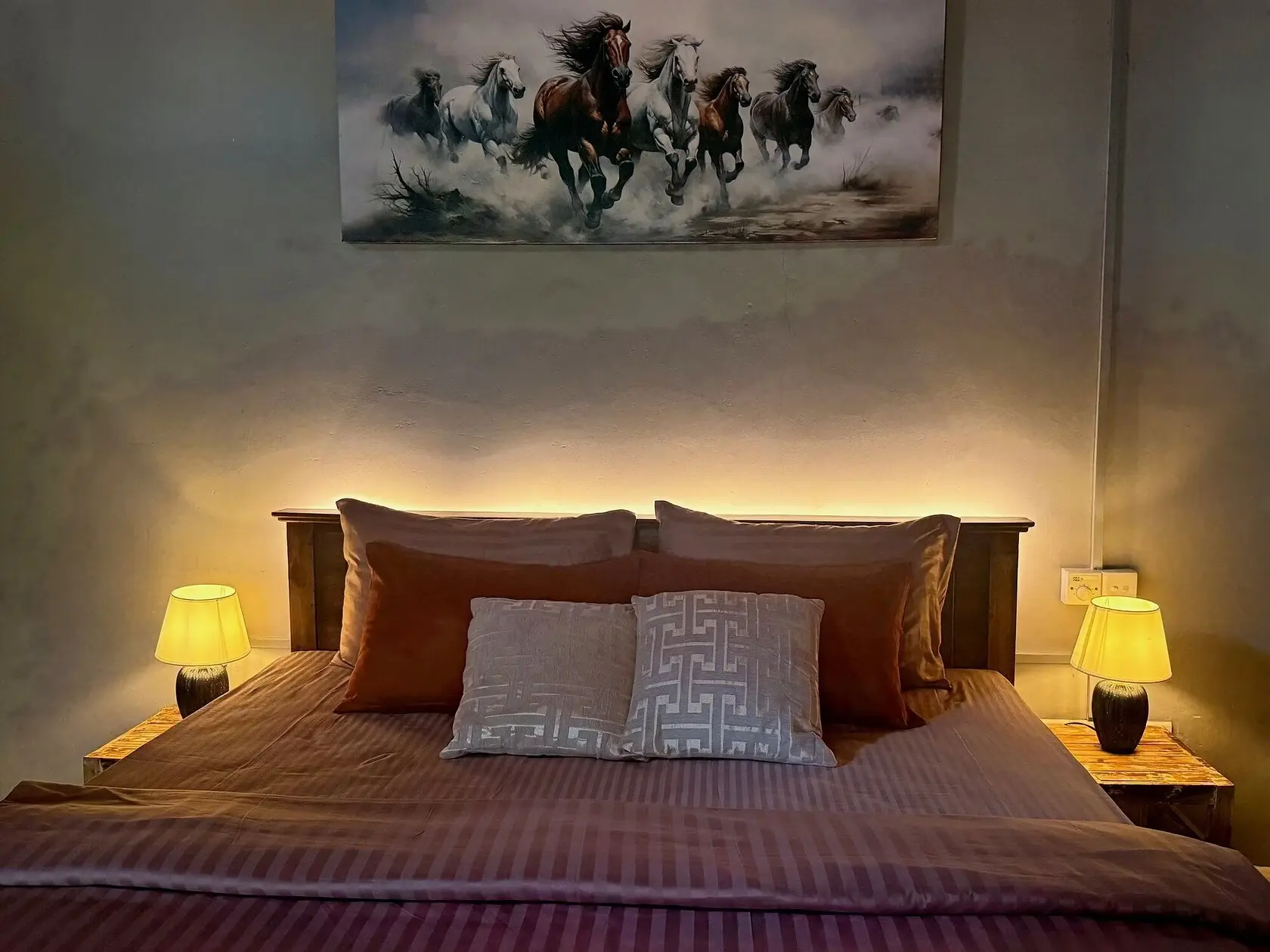 A ranch-house bedroom at Punanai, lamps lit either side of the bed.