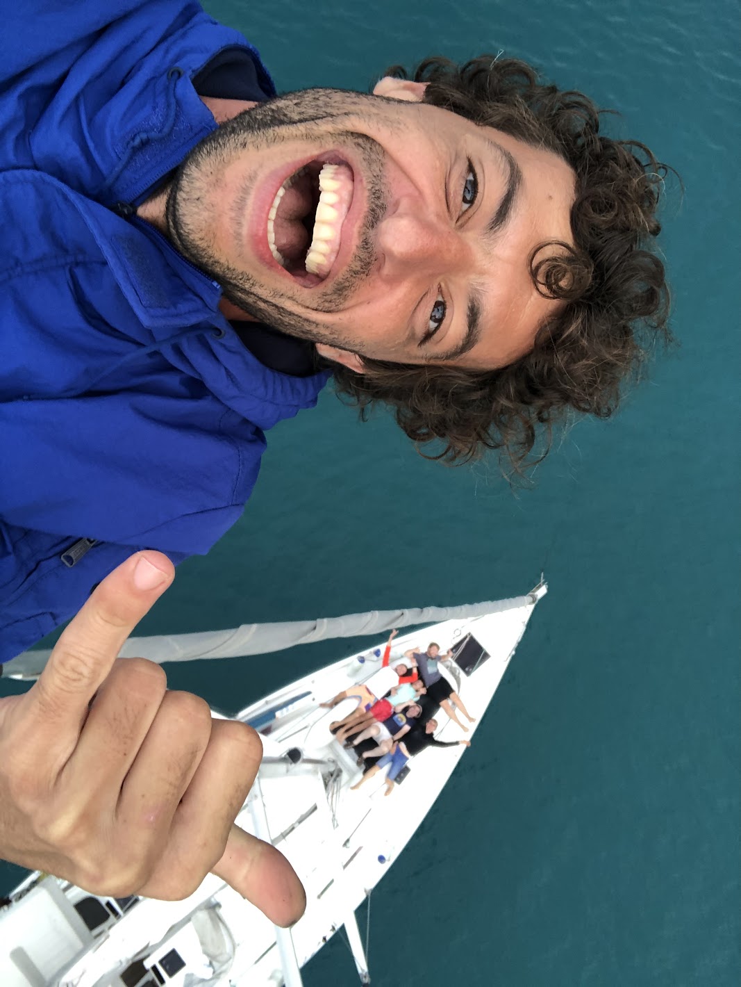 Guest smiling at the top of the mast above the yacht