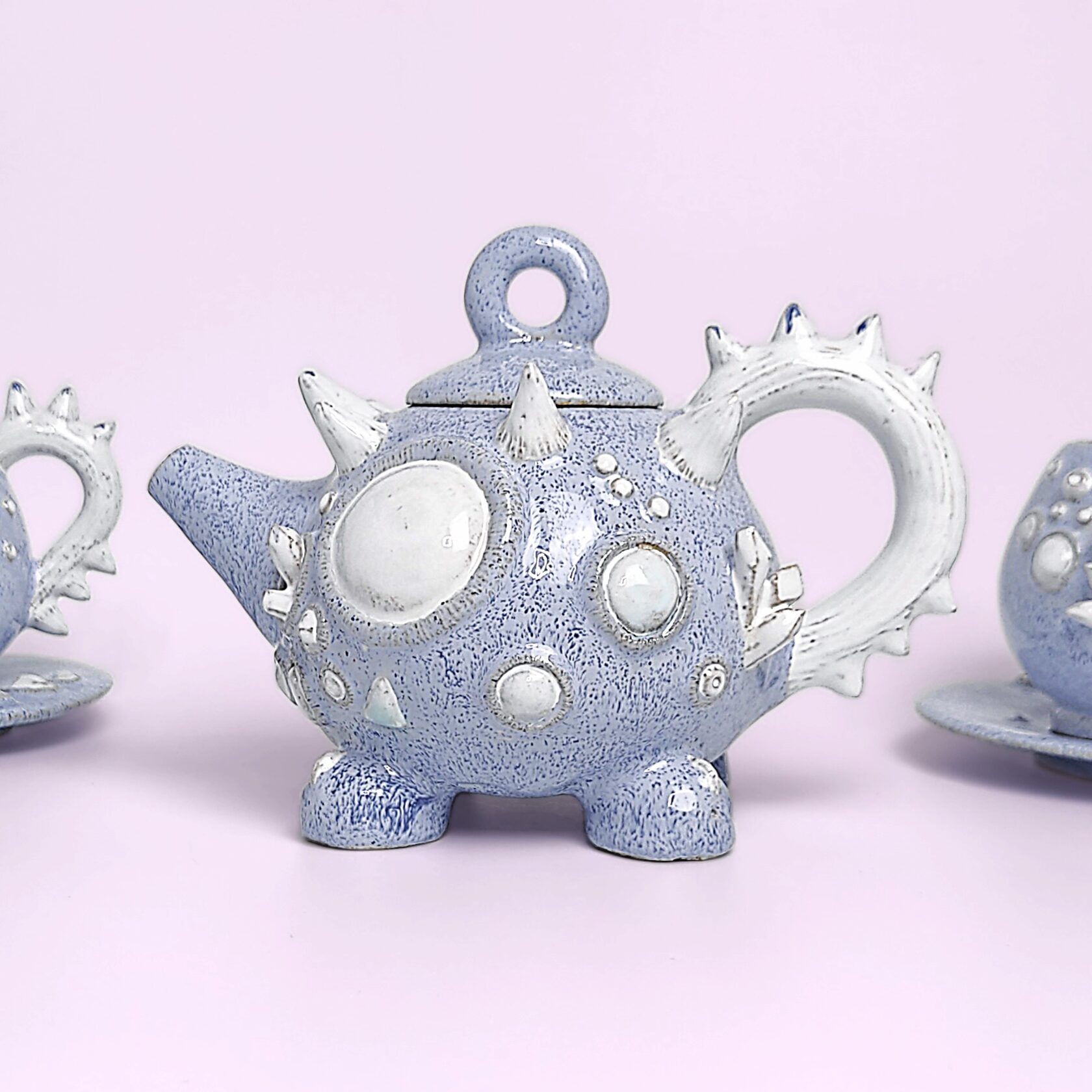 Unique handmade fairy-tale ceramic tea set shaped like a whimsical crystal-covered little monster, featuring a sculptural teapot and two matching cups with saucers