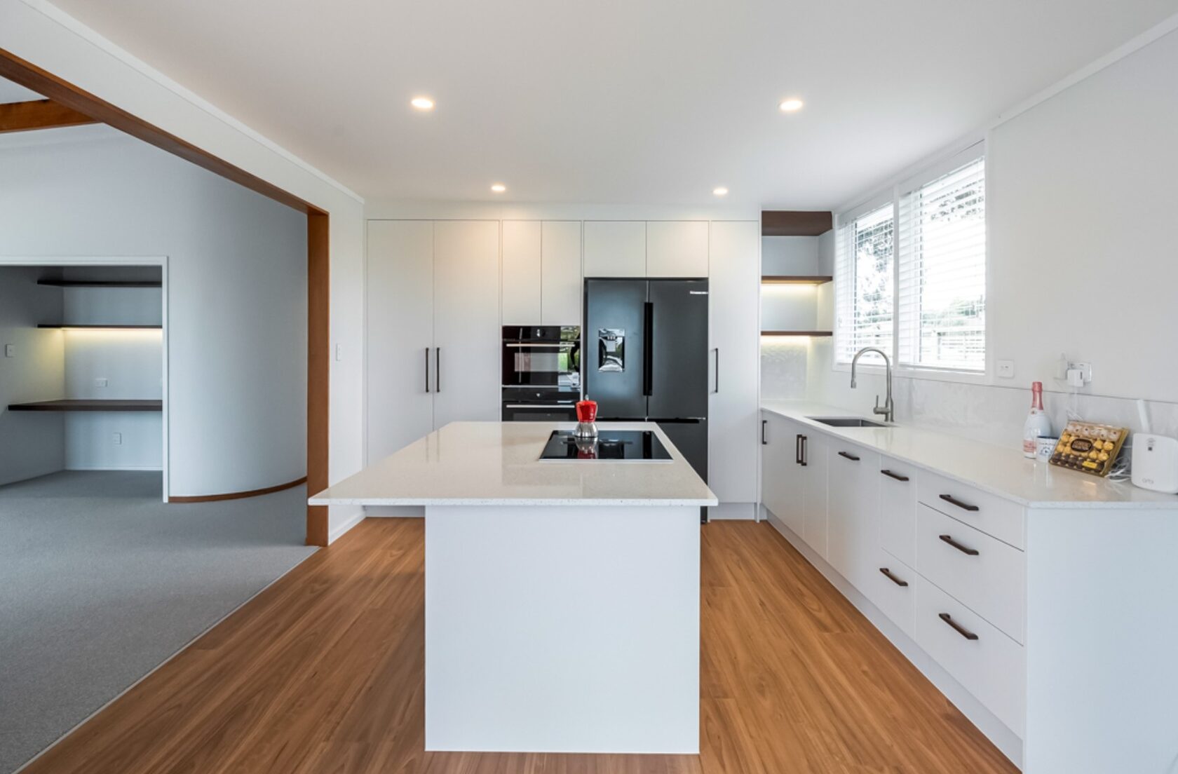 Completed Hillcrest kitchen with white cabinetry, an island, black refrigerator and timber flooring
