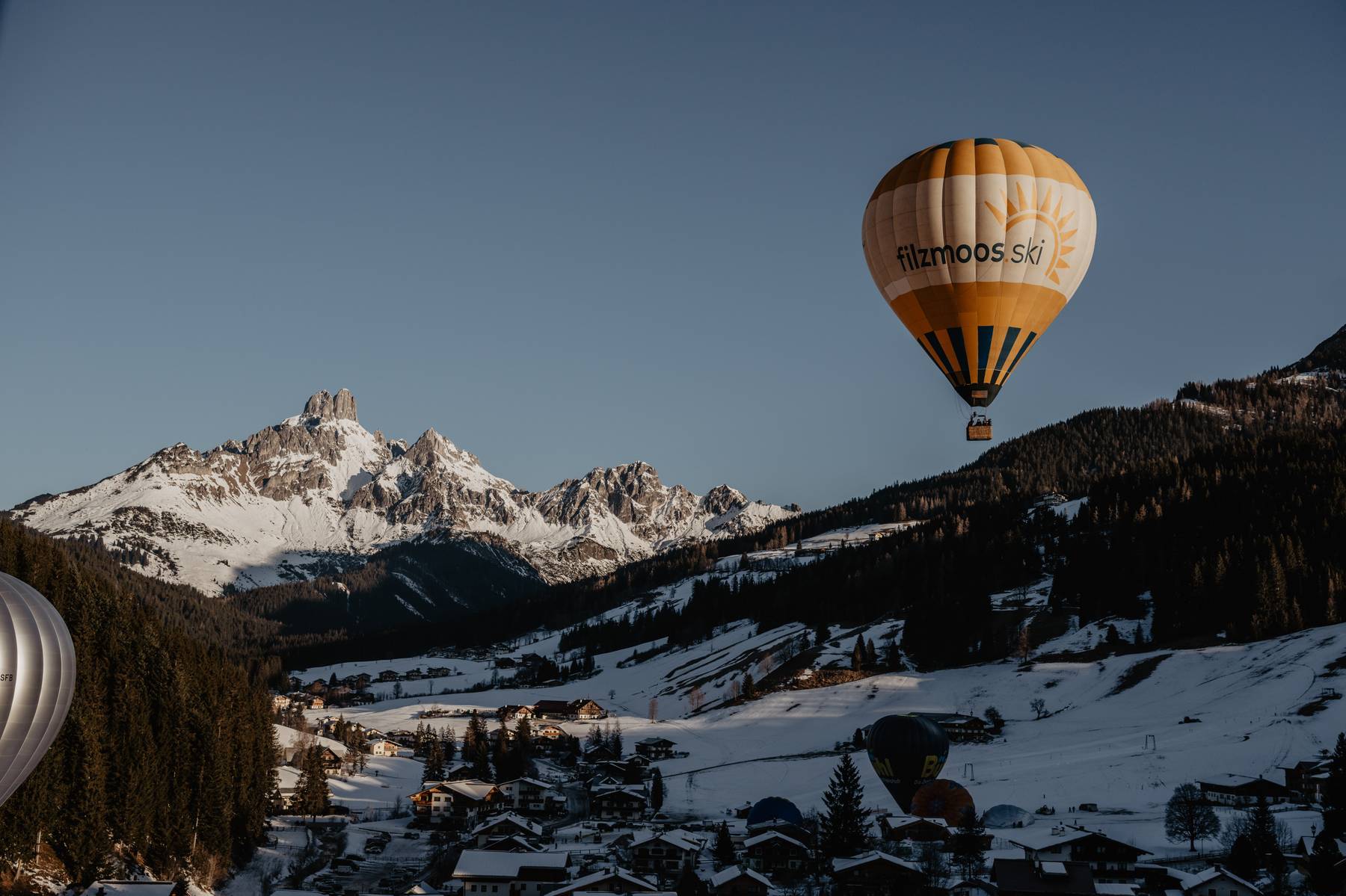 Hot air balloon above Filzmoos with snowy alpine peaks in the Austrian mountains
