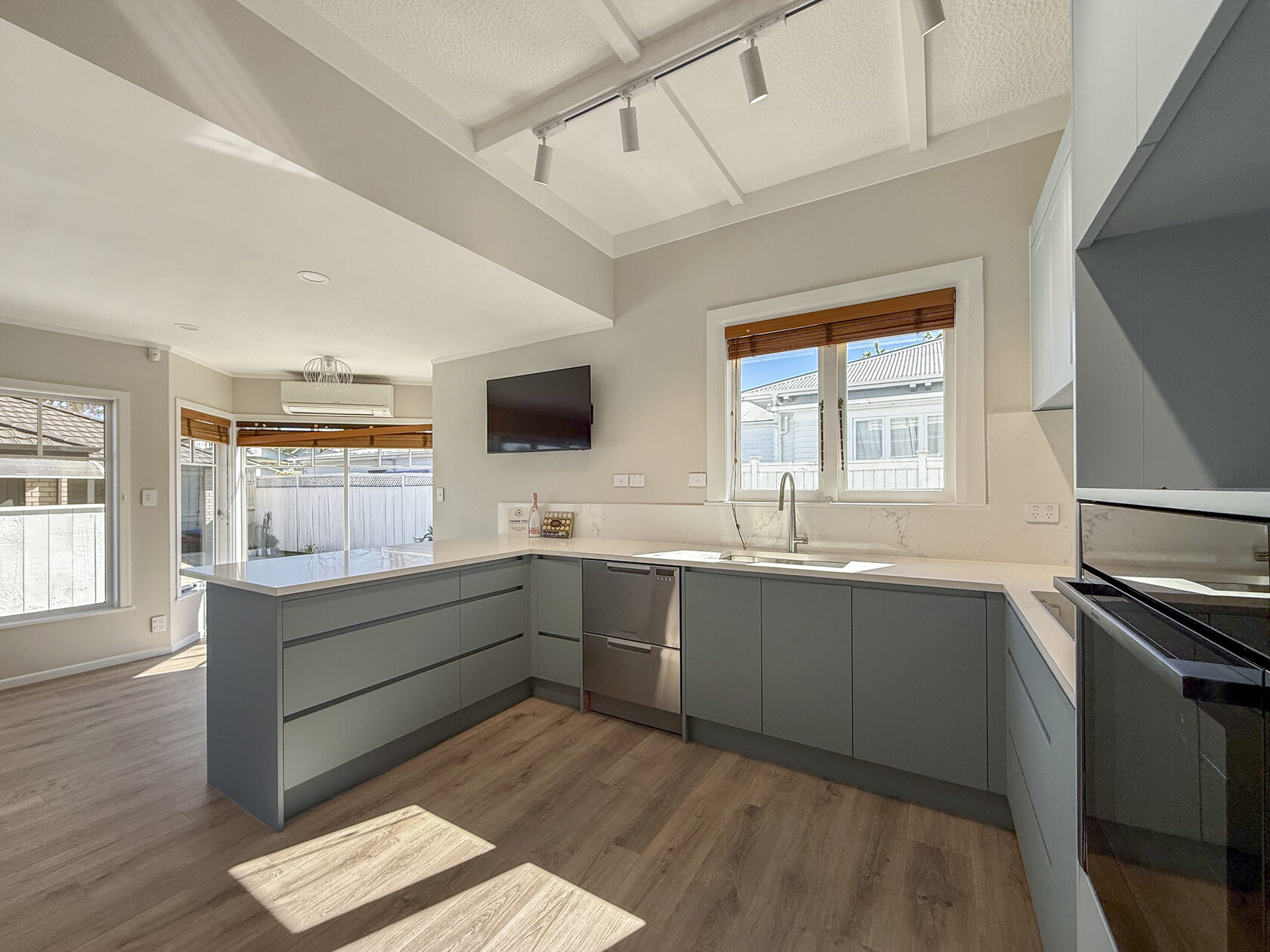 Renovated kitchen with muted green cabinetry, white worktops and a peninsula