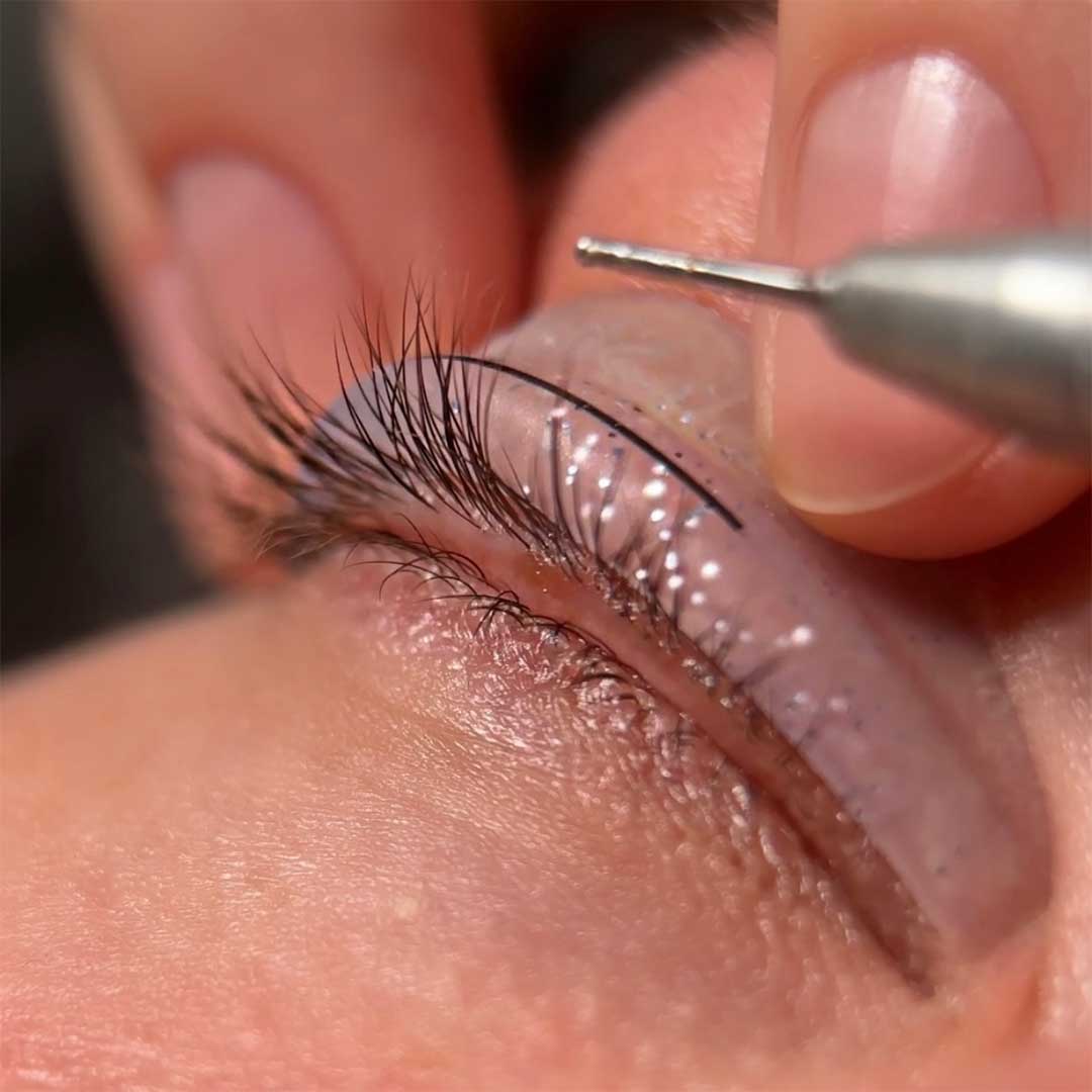 Yulia utilizando una herramienta especializada para analizar y preparar las pestañas antes de realizar el lifting. La herramienta ayuda a evaluar la forma y condición de las pestañas para un tratamiento preciso y personalizado.