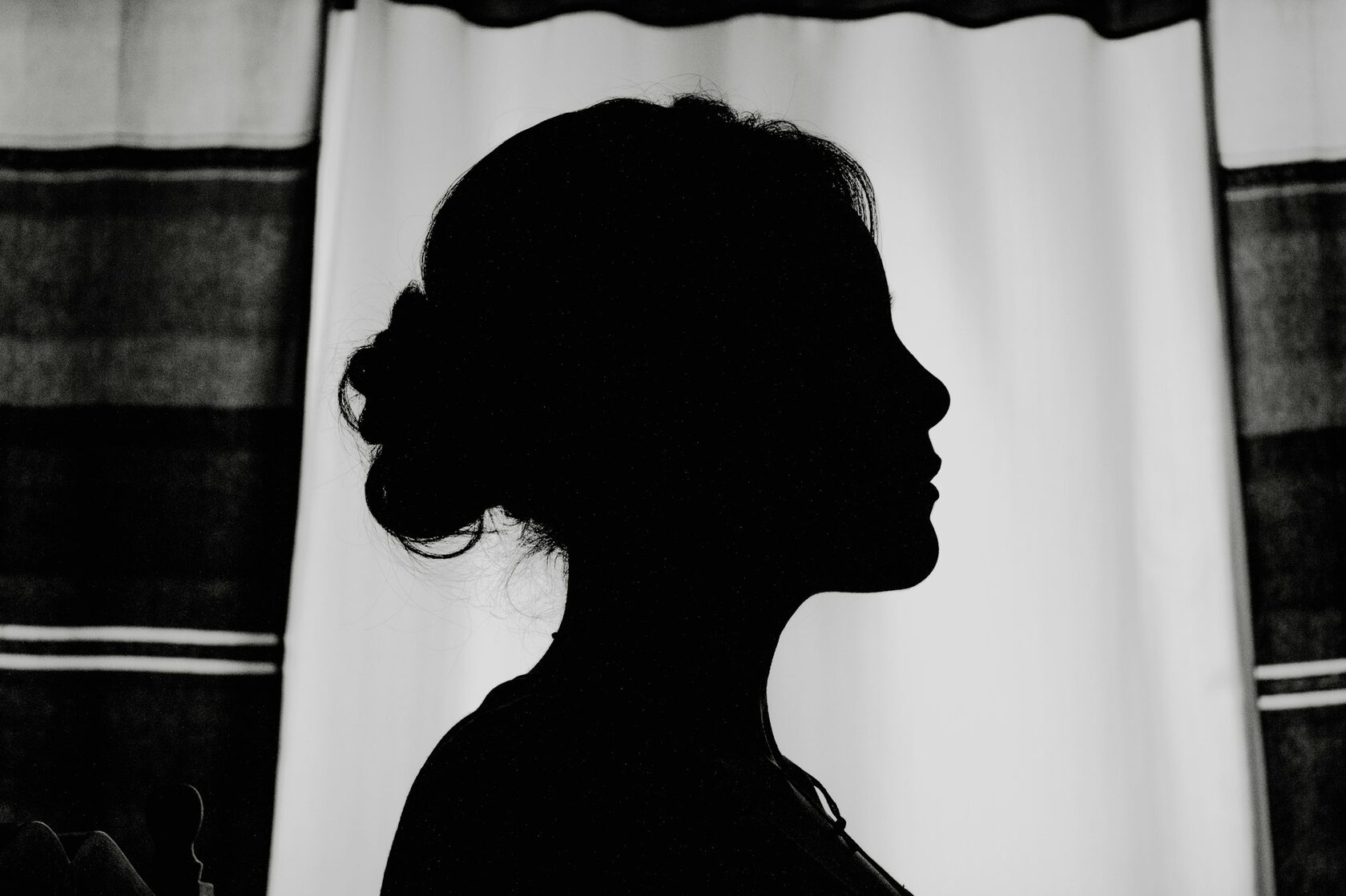 A woman in silhouette standing by a window in soft light