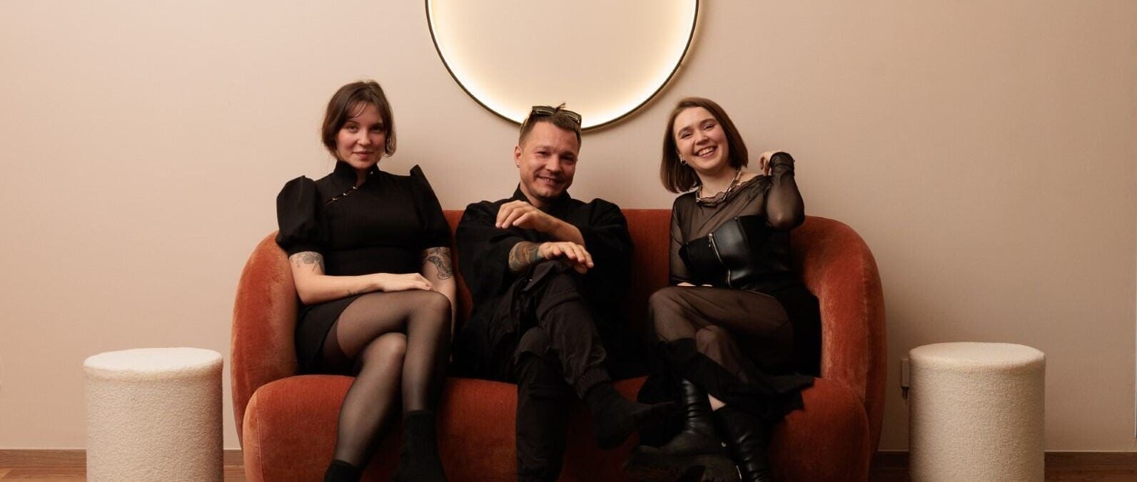 Das Team des INTO Tattoo Studio in Wien auf dem orangefarbenen Sofa