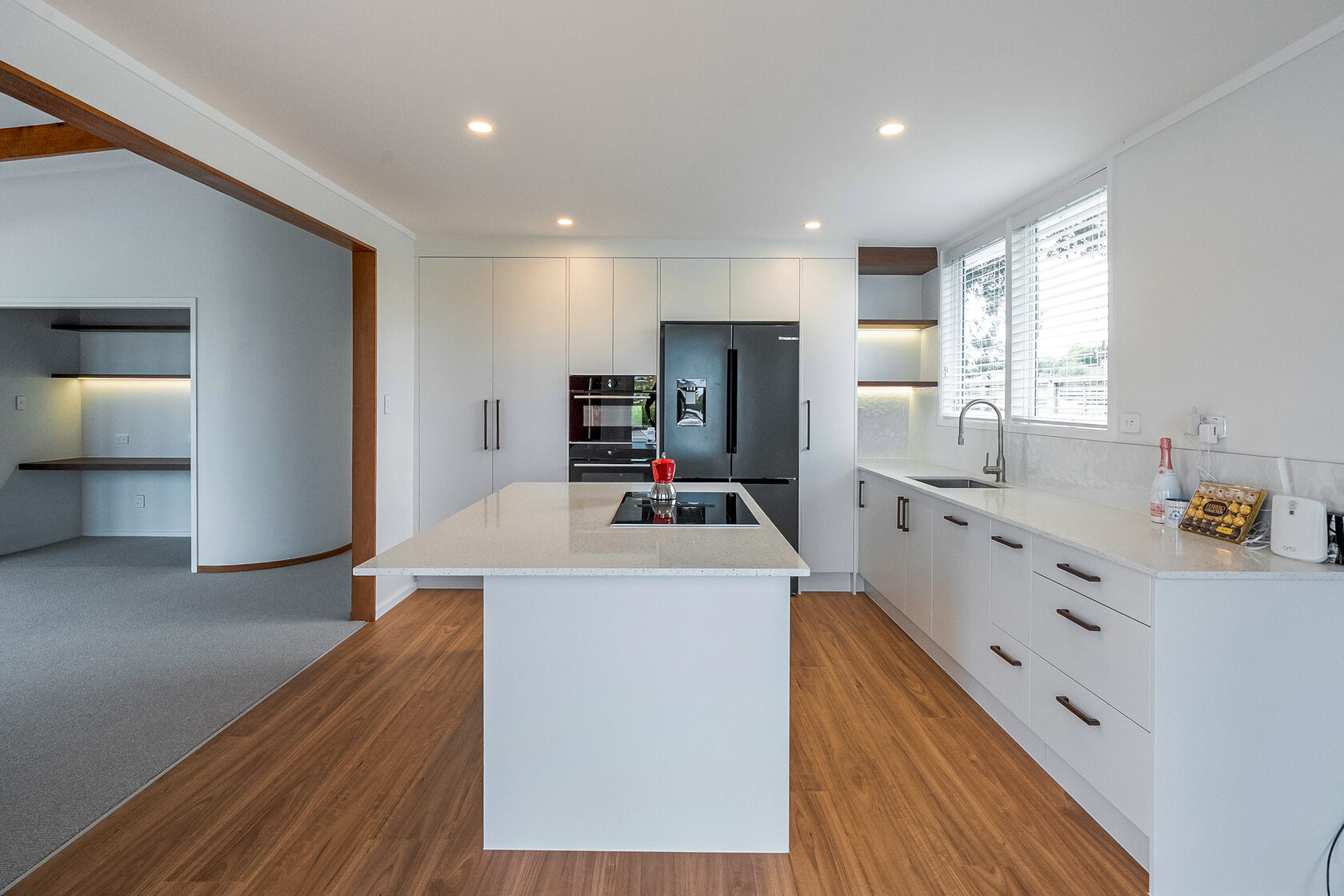 Renovated Hillcrest kitchen with white cabinetry, a central island, pale benchtops and warm timber flooring