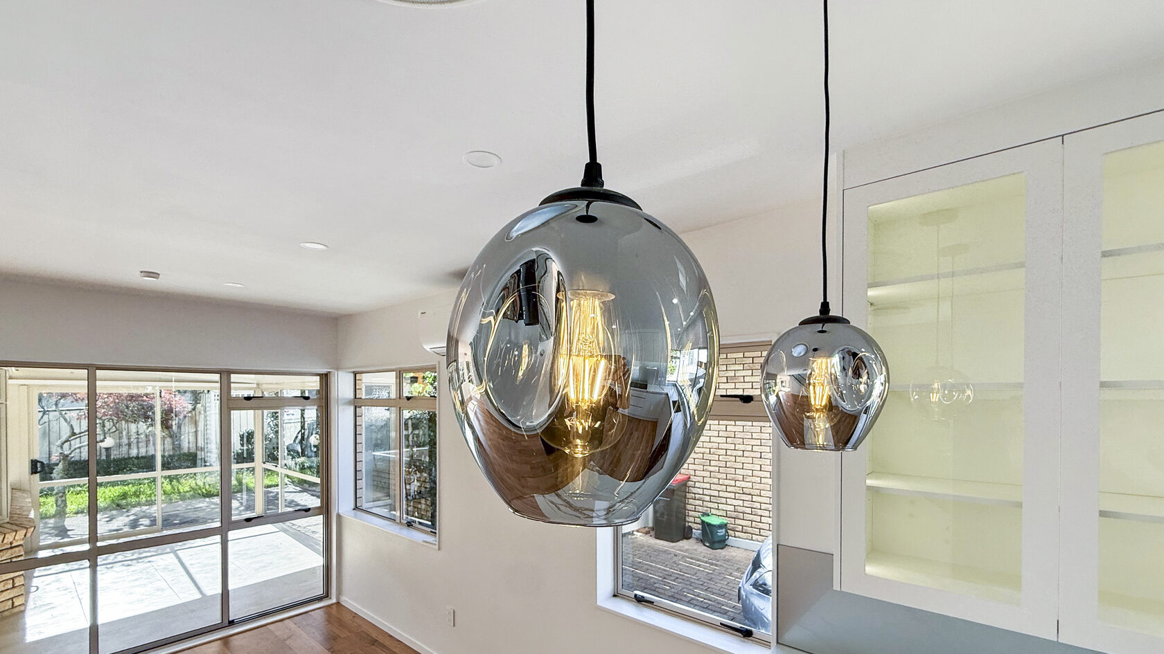 Glass pendant lights above the renovated kitchen in St Heliers, Eastern Bays.