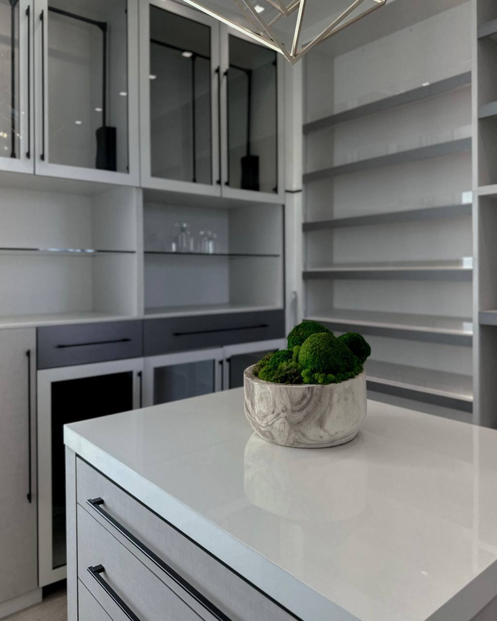 A bowl of moss balls on a butler's pantry island with empty display shelving behind it