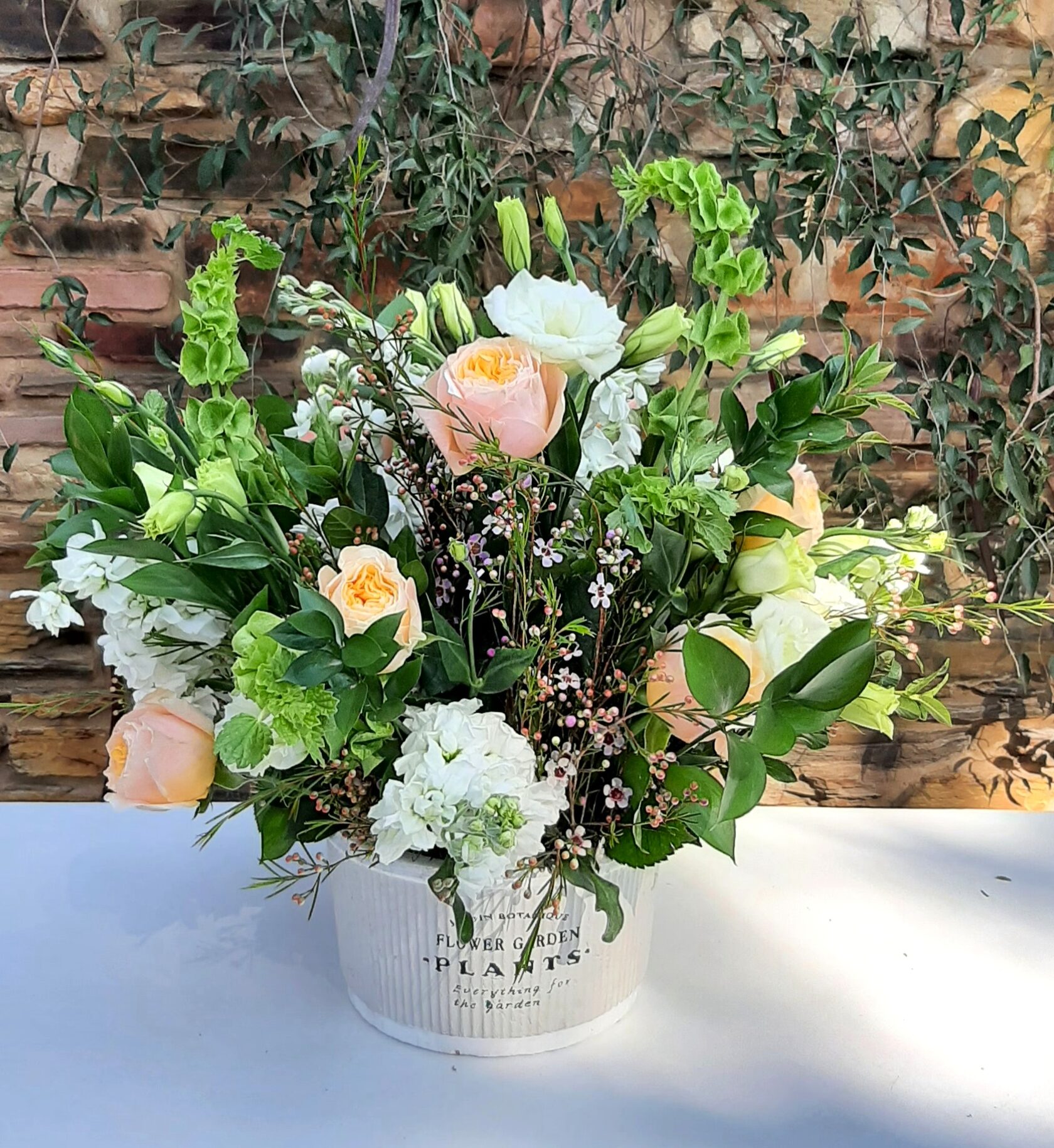 a delicate floral arrangement of peach roses, white hydrangea, and green flower clusters