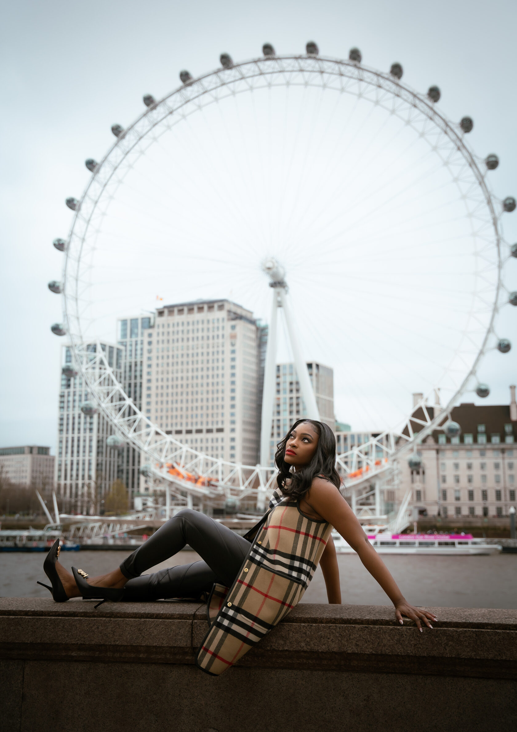 Woman seated by the Thames with the London Eye behind