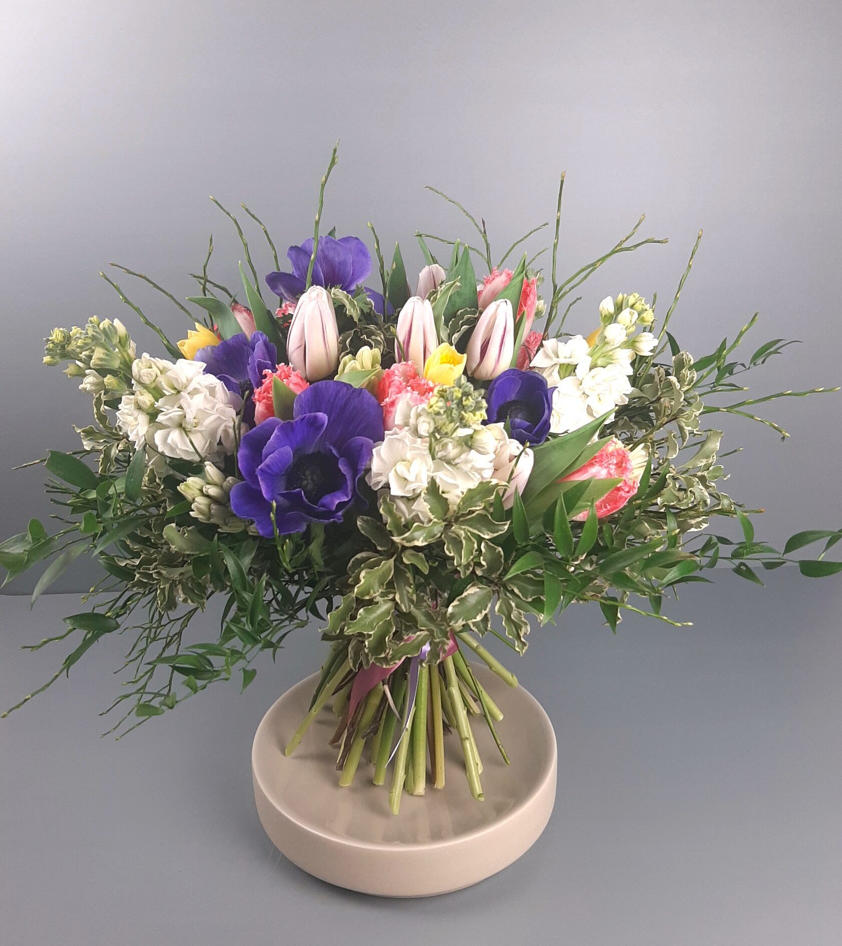 a beautiful mixed bouquet featuring bright purple anemones with dark centers and pale pink ones