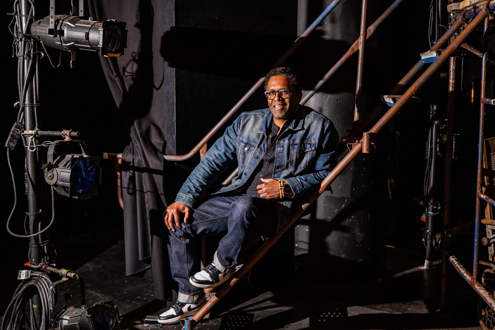 Lindsay Smiling sitting on backstage stairs among stage lights