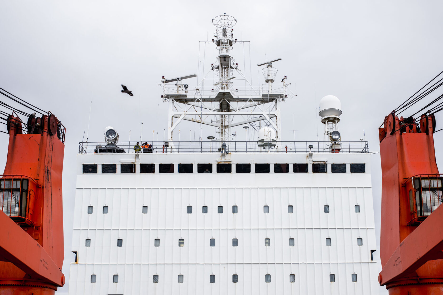 Research vessel bridge between orange cranes