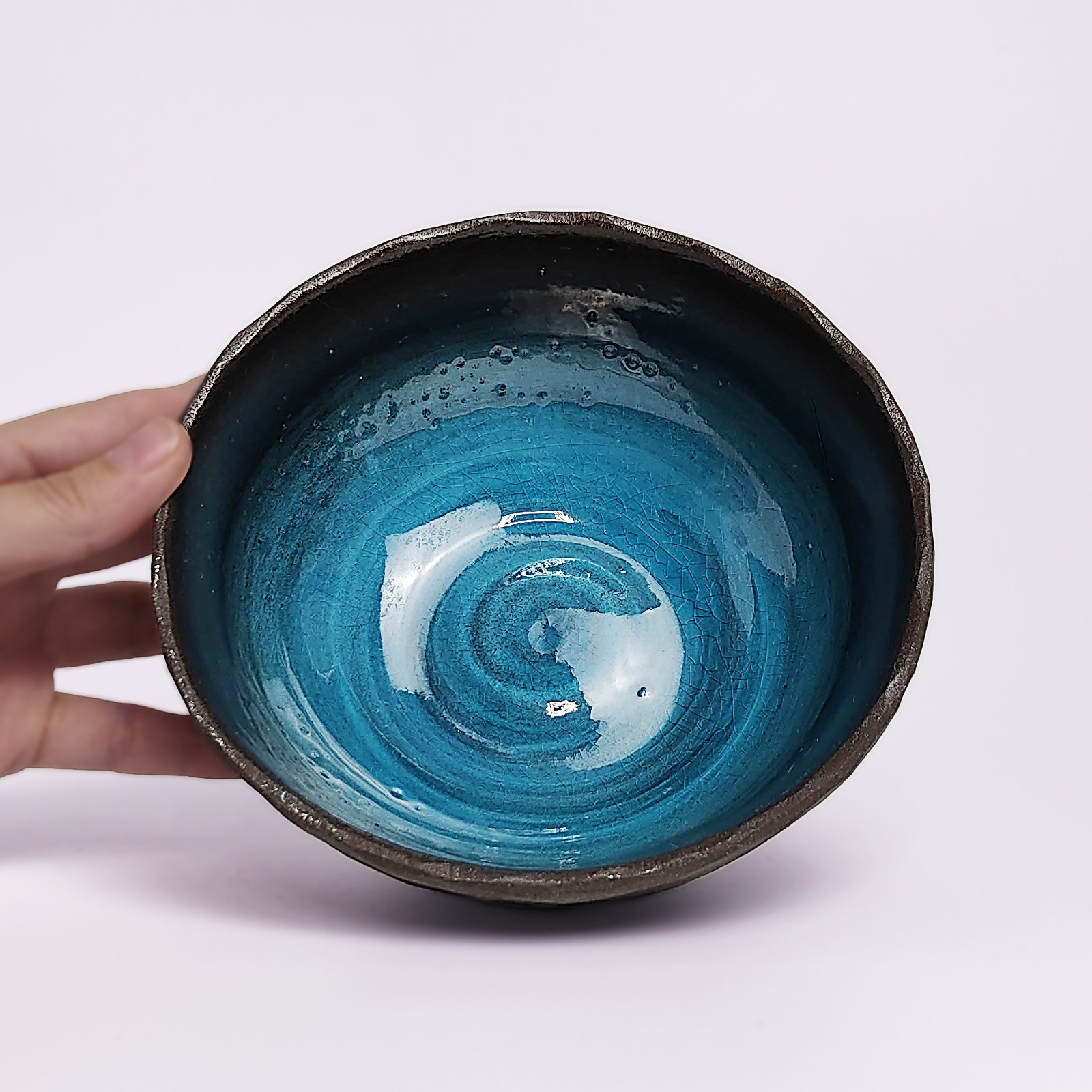 unique handmade ceramic bowl with dark clay exterior and vibrant deep blue glaze, artistic decorative tableware