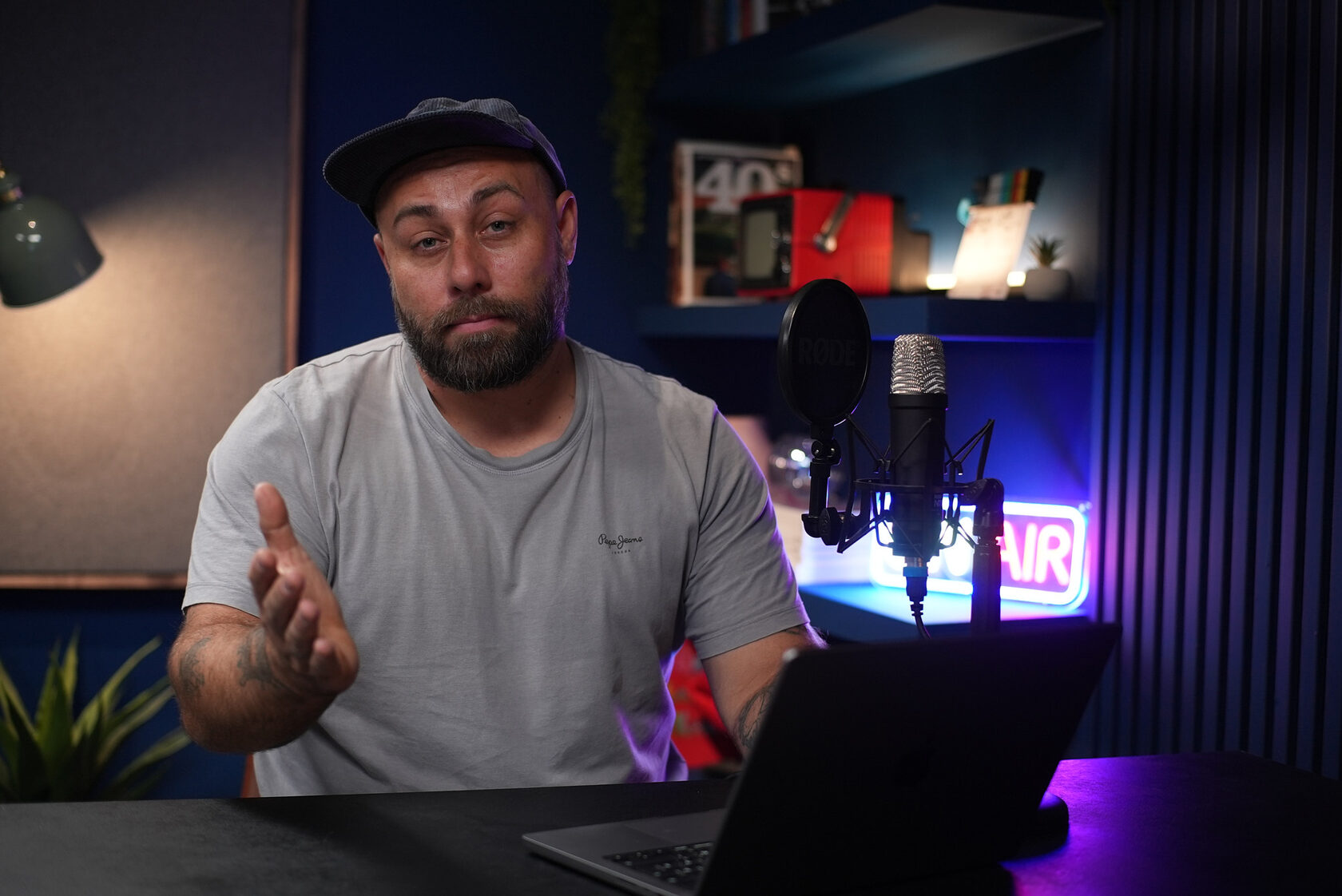 Govornik uz mikrofon i laptop u plavom enterijeru sa natpisom ON AIR