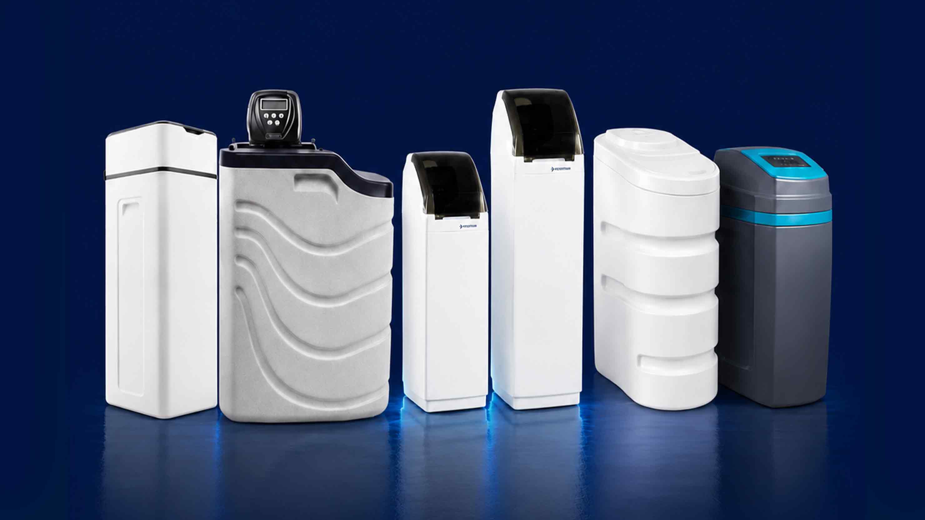 The image shows different models of water softeners against the background of a comparison table of their performance indicators.