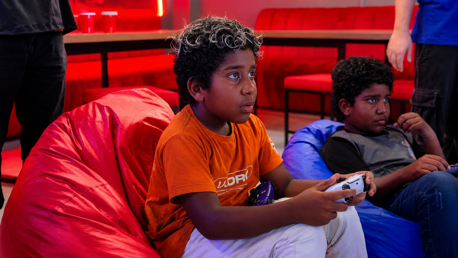 Crianças jogando PlayStation na área lounge da OVA