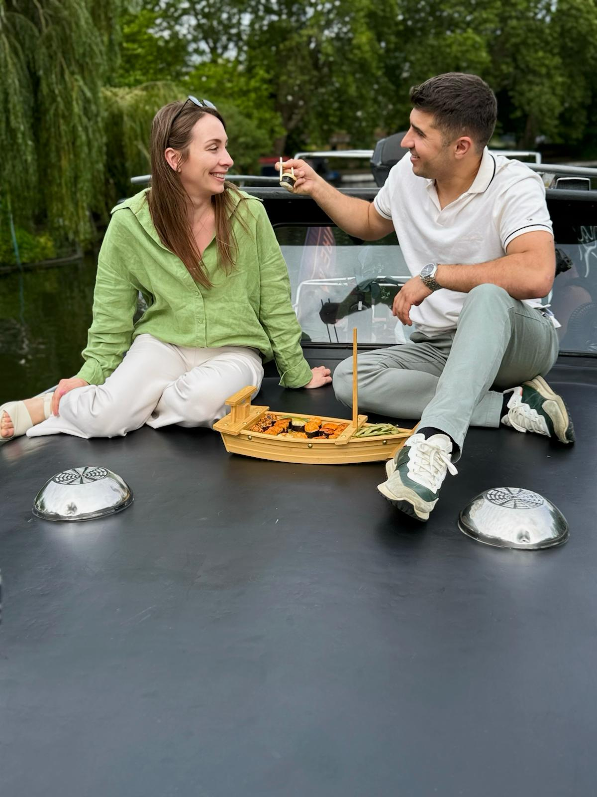 Couple sharing sushi on boat roof