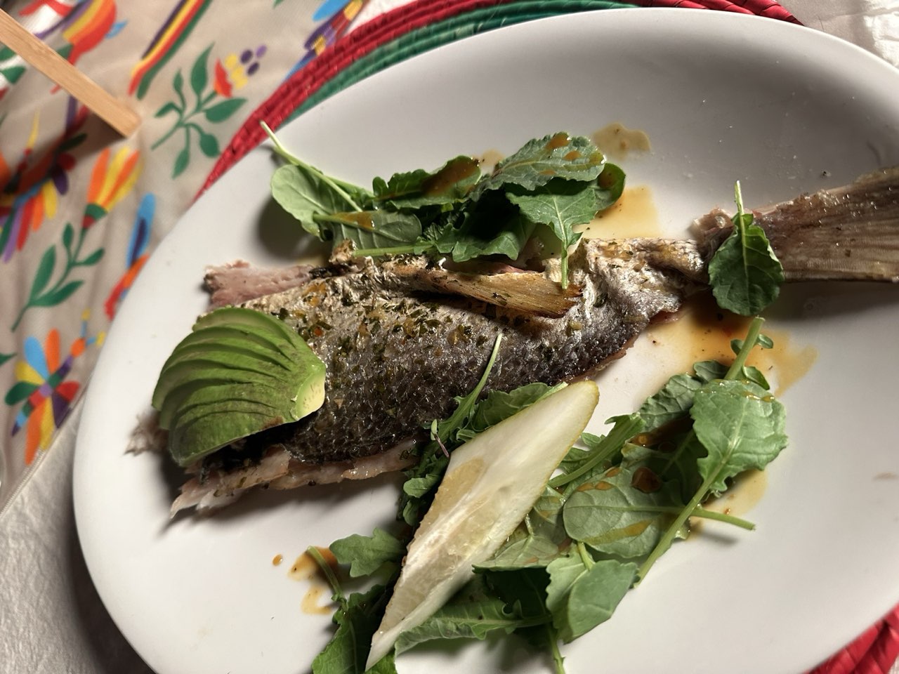 Pescado con hojas verdes sobre mantel bordado