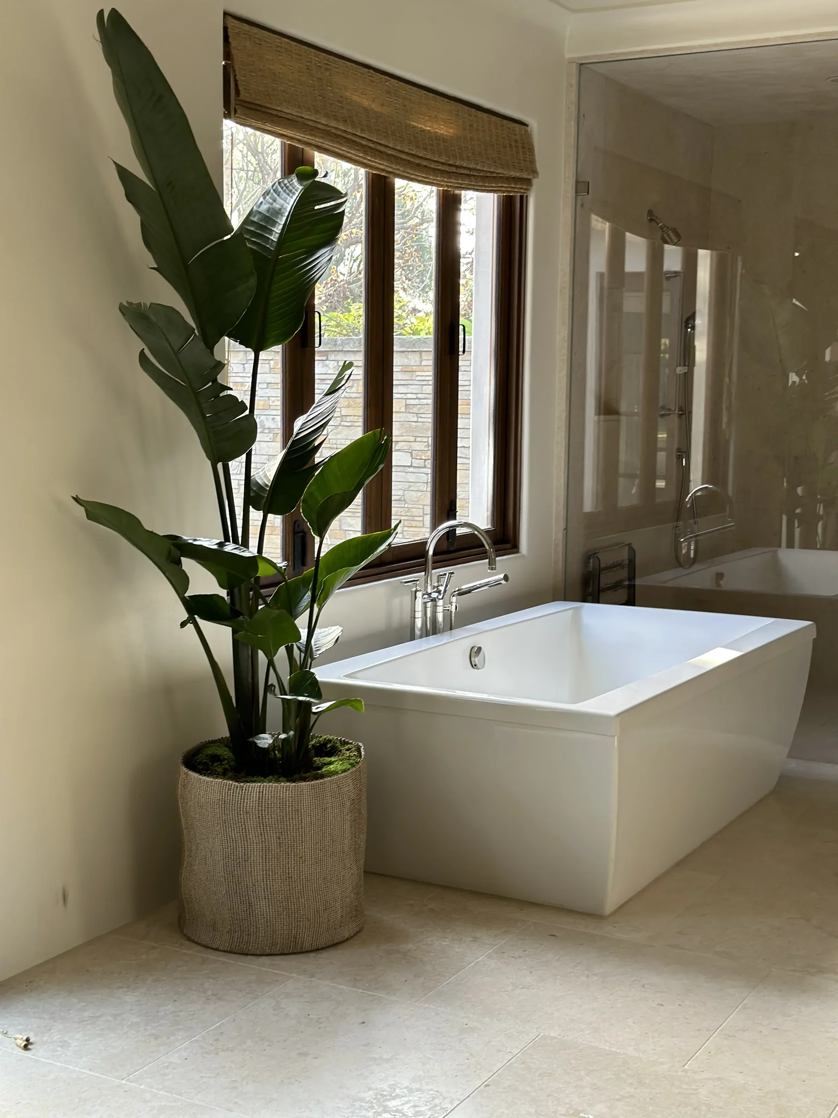 Bird of paradise beside a freestanding tub in a staged bathroom