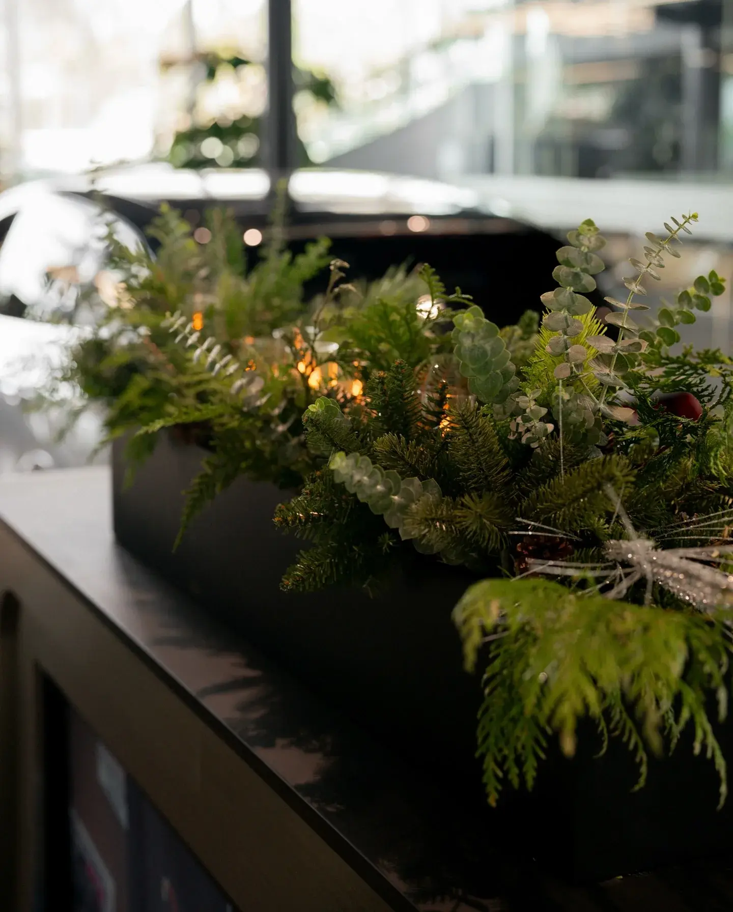 Evergreen branches with warm lights in a desk planter