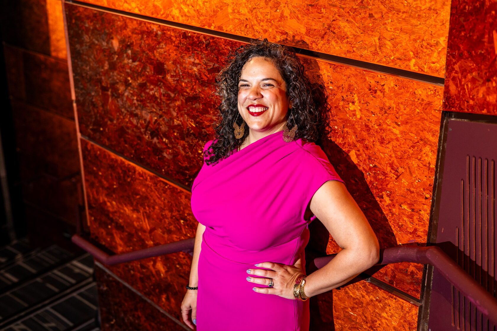Leigh Goldenberg in a magenta dress against an orange wall