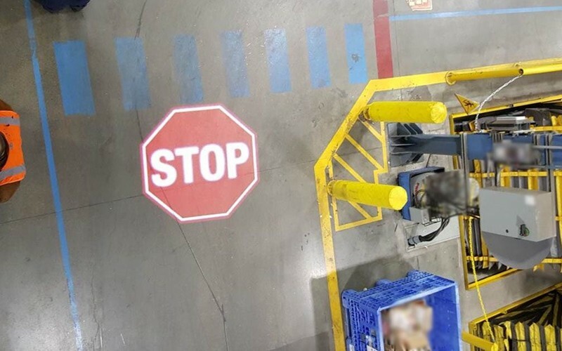High-contrast projected floor marking in a warehouse aisle