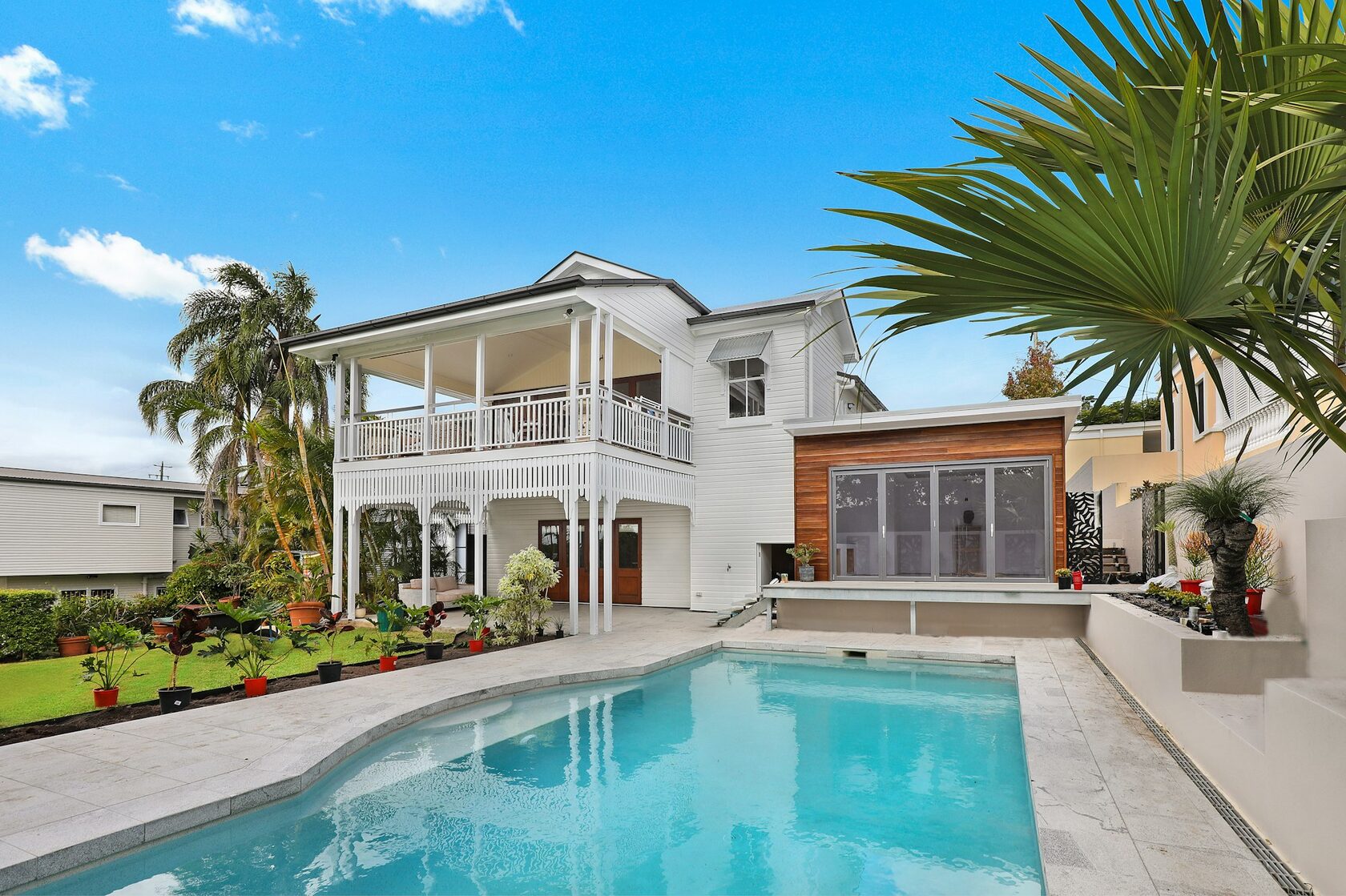 A two-story pool enclosure meeting a second-floor balcony