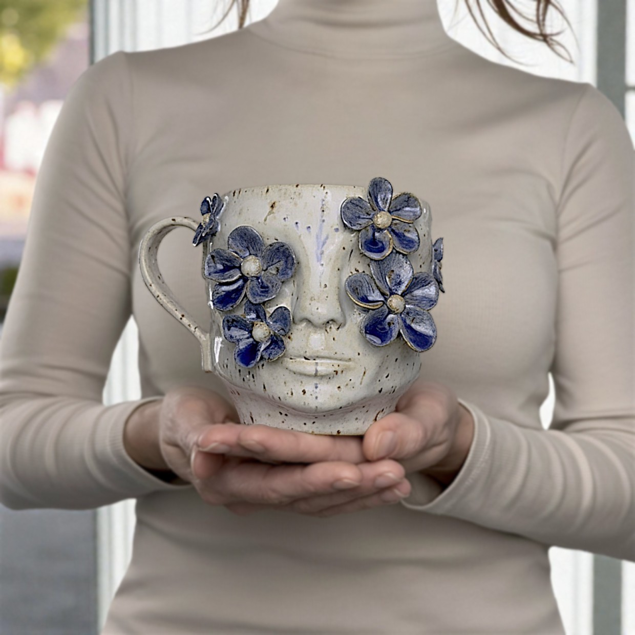 Handmade ceramic face mug with sculpted blue flowers, artist-designed pottery cup for tea or coffee