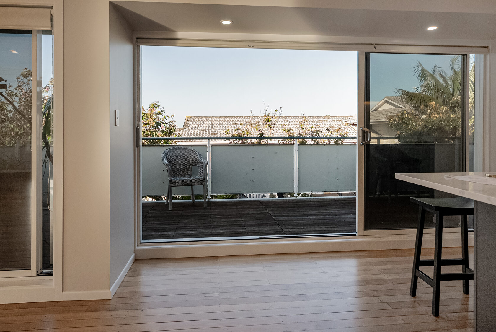 View across the Glenfield kitchen benchtop toward wide sliding doors and the deck