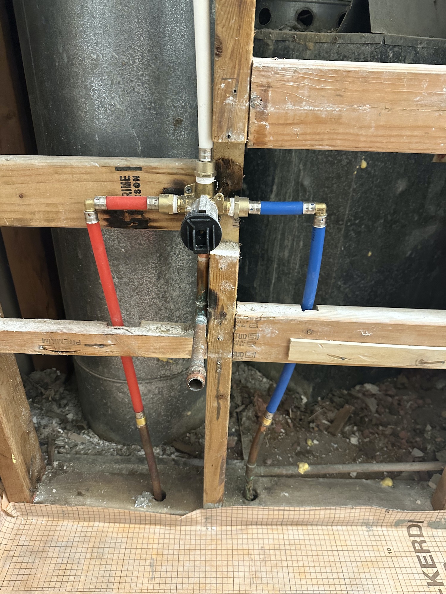 Open bathroom wall showing framing and shower plumbing during Austin bathroom remodel