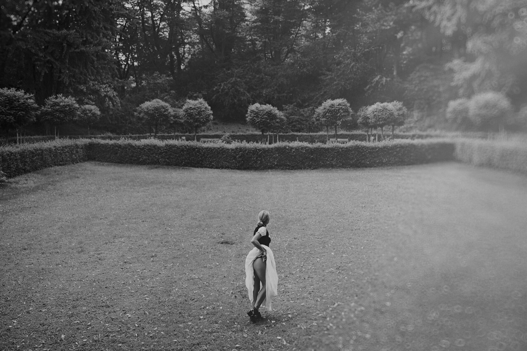 Künstlerische Schwarz-Weiß-Aufnahme einer Frau im Dirndl in einer Gartenlandschaft