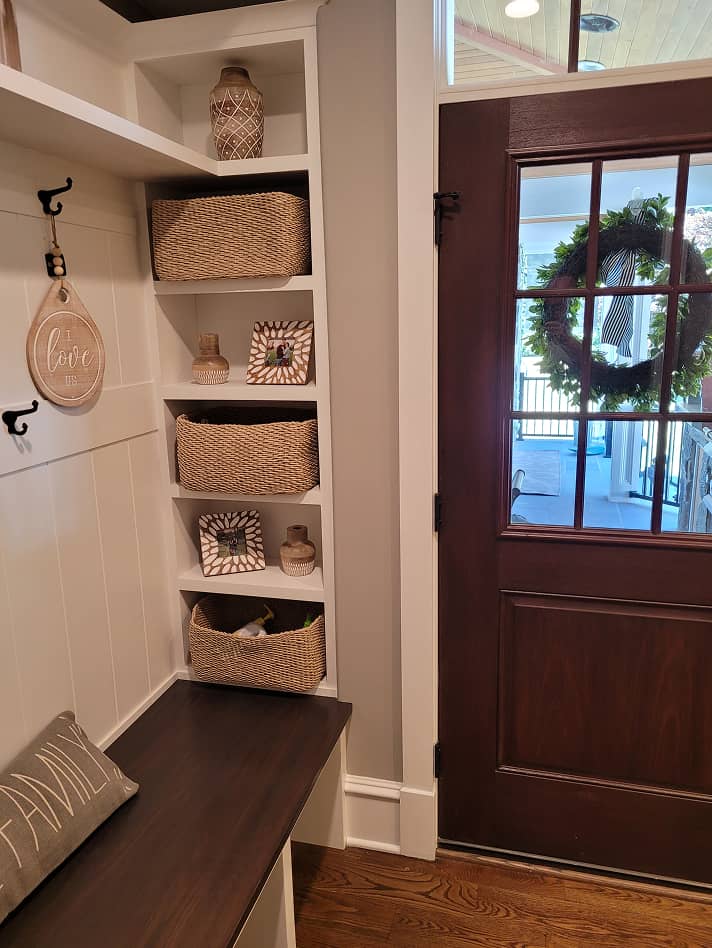 Mudroom shelves and built-in dark stained bench furnished with baskets and hooks 