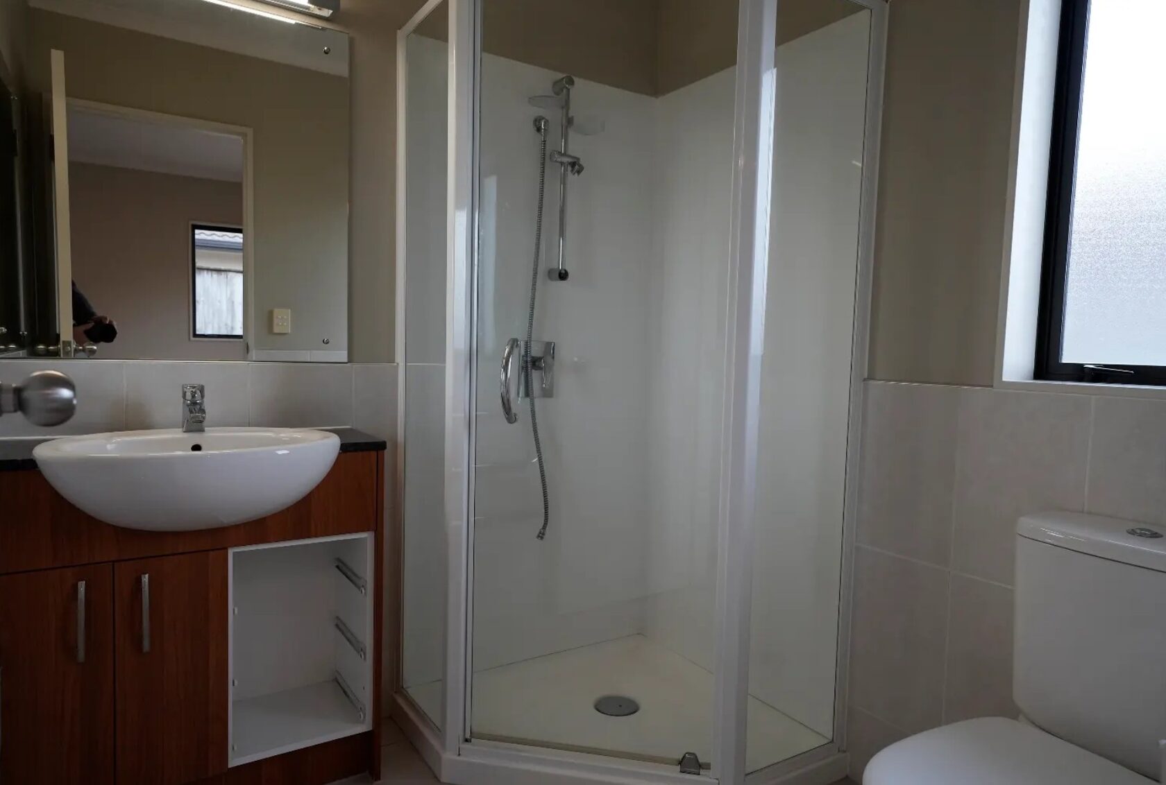 Before: Original ensuite with a framed shower enclosure, timber vanity, white basin and toilet