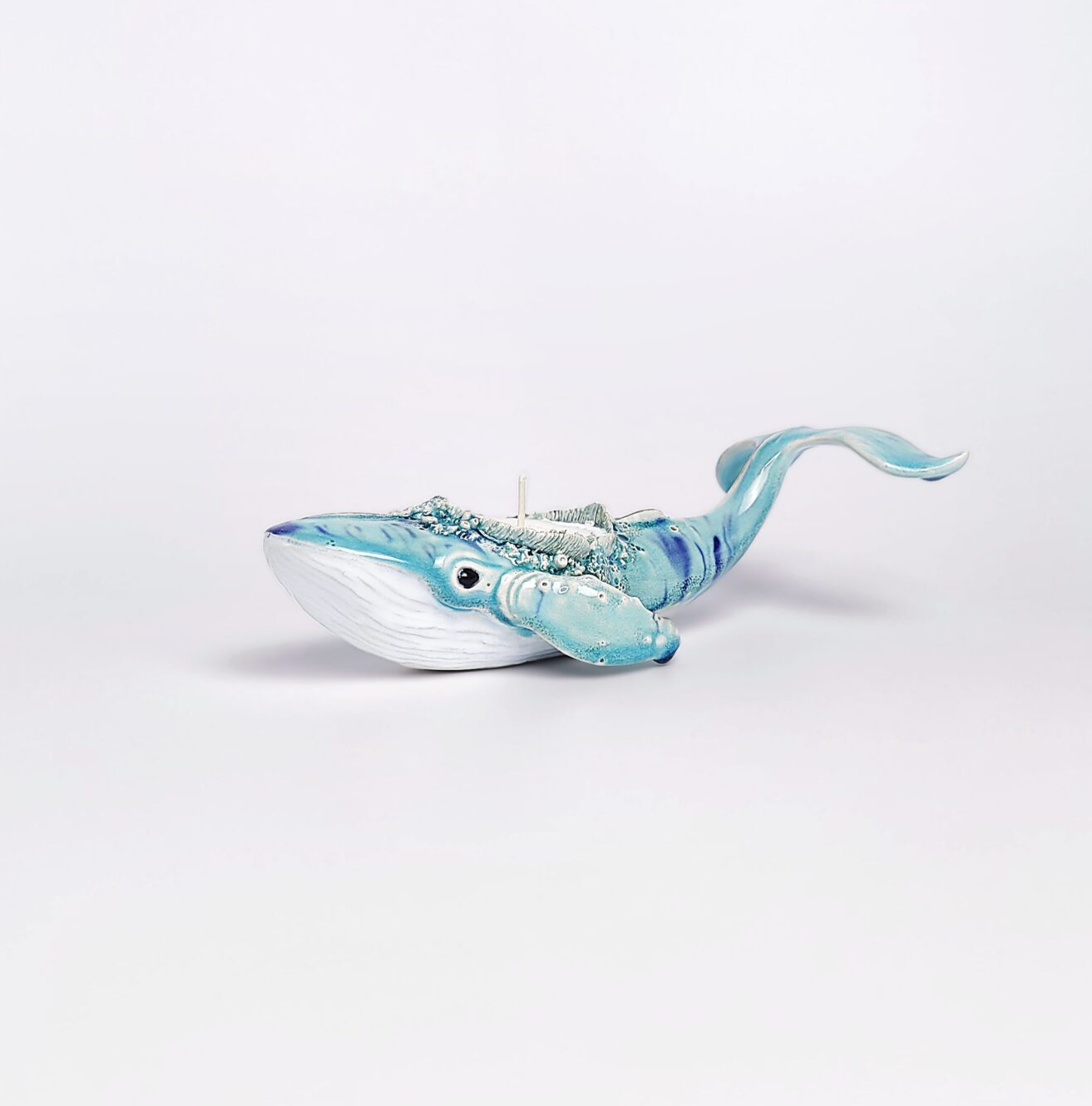 Unique handmade ceramic whale candle holder with ocean-blue glaze, detailed sculptural texture, and a built-in candle