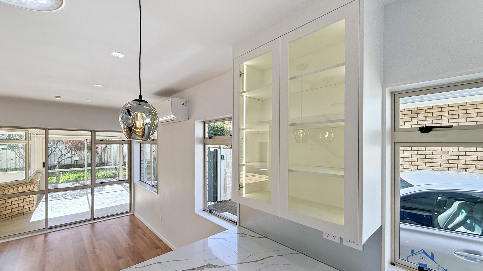 Glass-front kitchen cabinets and pendant lighting in the St Heliers renovation.