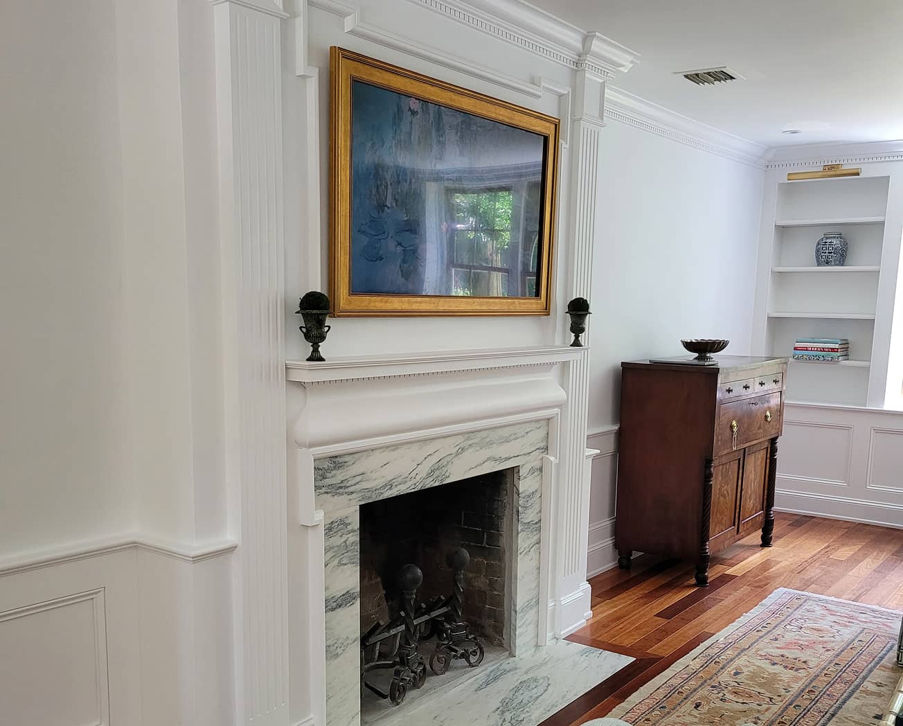 Living room fireplace with historic paneling and built-in shelves.