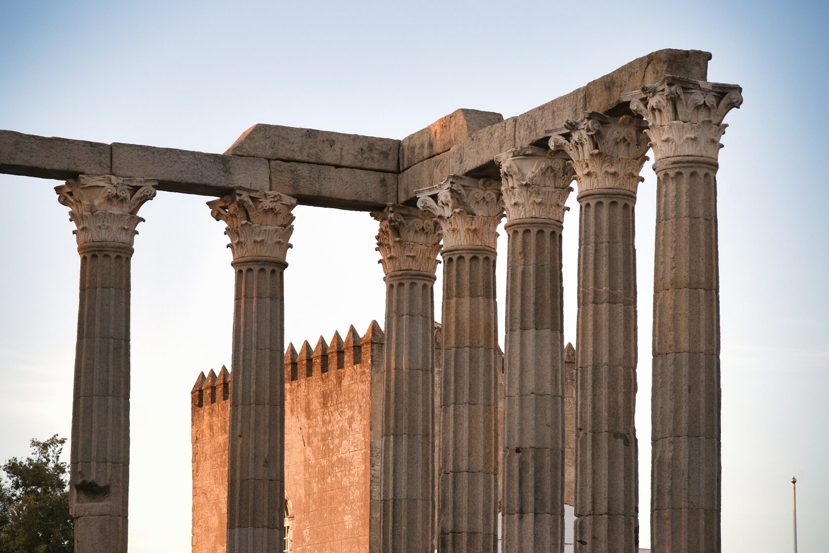 The Roman Temple of Évora at golden hour, its granite columns glowing against a deep blue sky