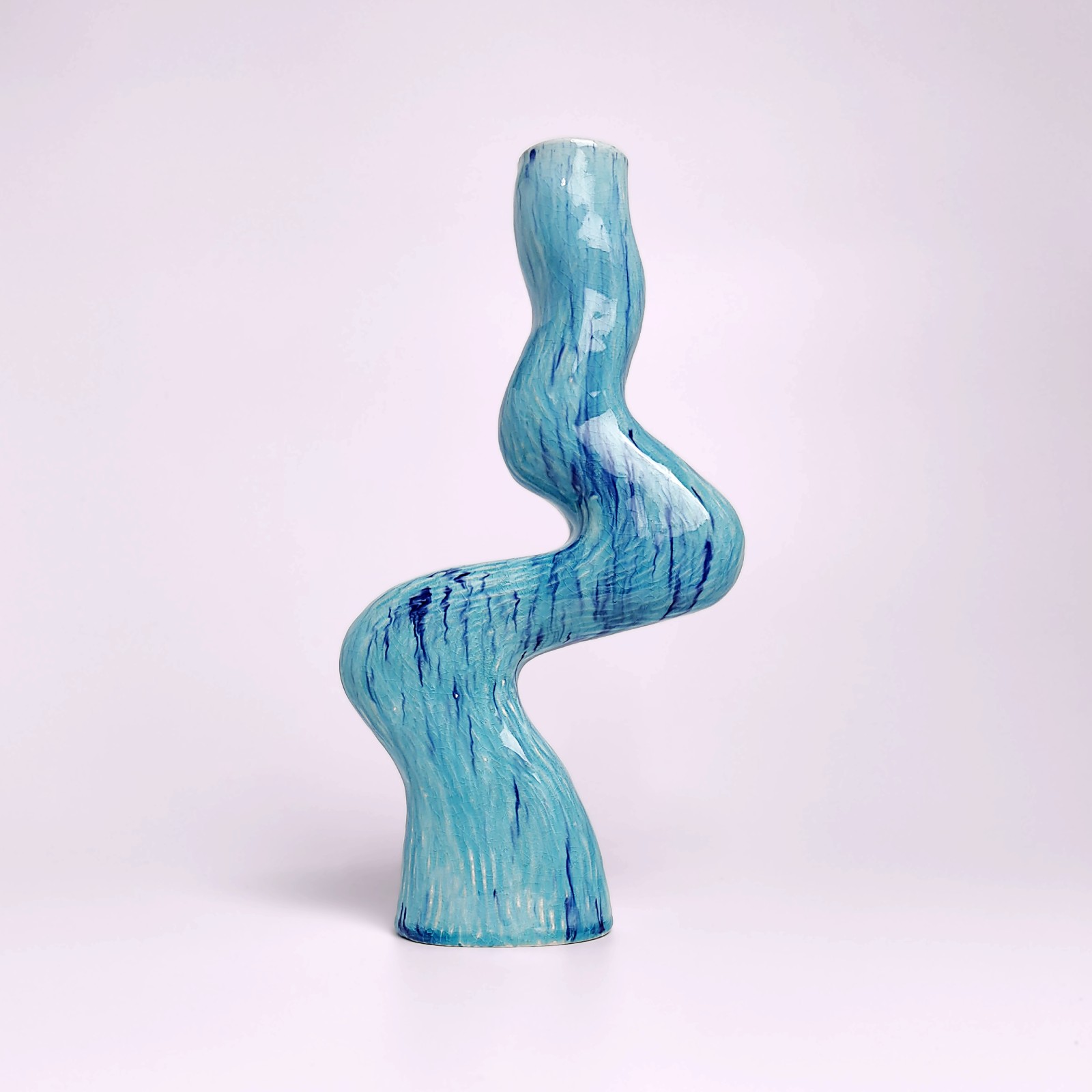 unique handmade ceramic candle holder for a single candle, featuring an organic wavy shape and blue glaze with watercolor-like drips