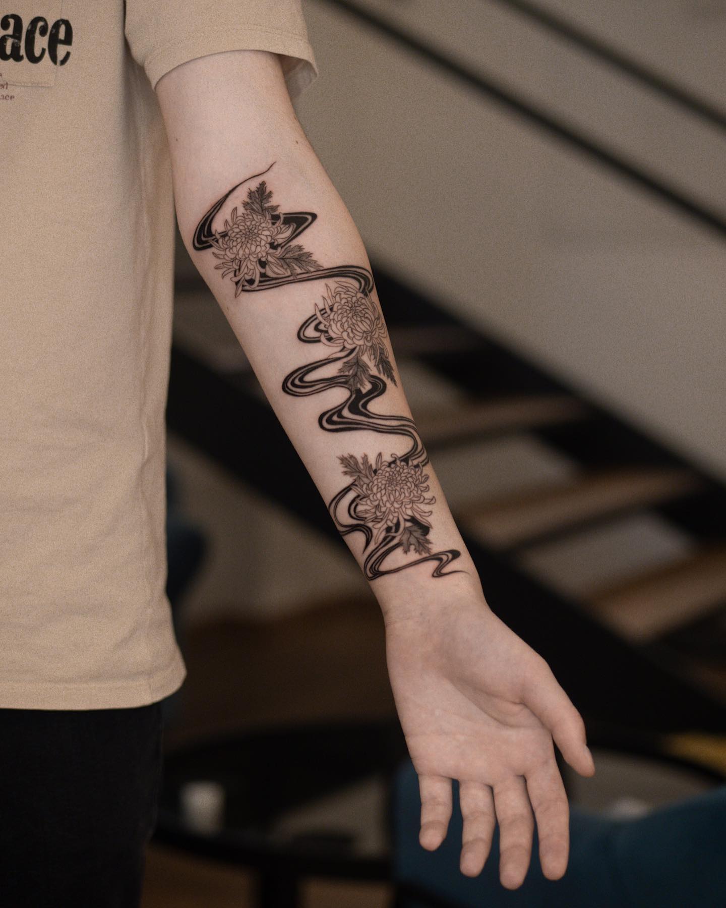 Chrysanthemen mit fließendem Band, Floral-Tattoo von Anna im INTO Tattoo Studio in Wien.
