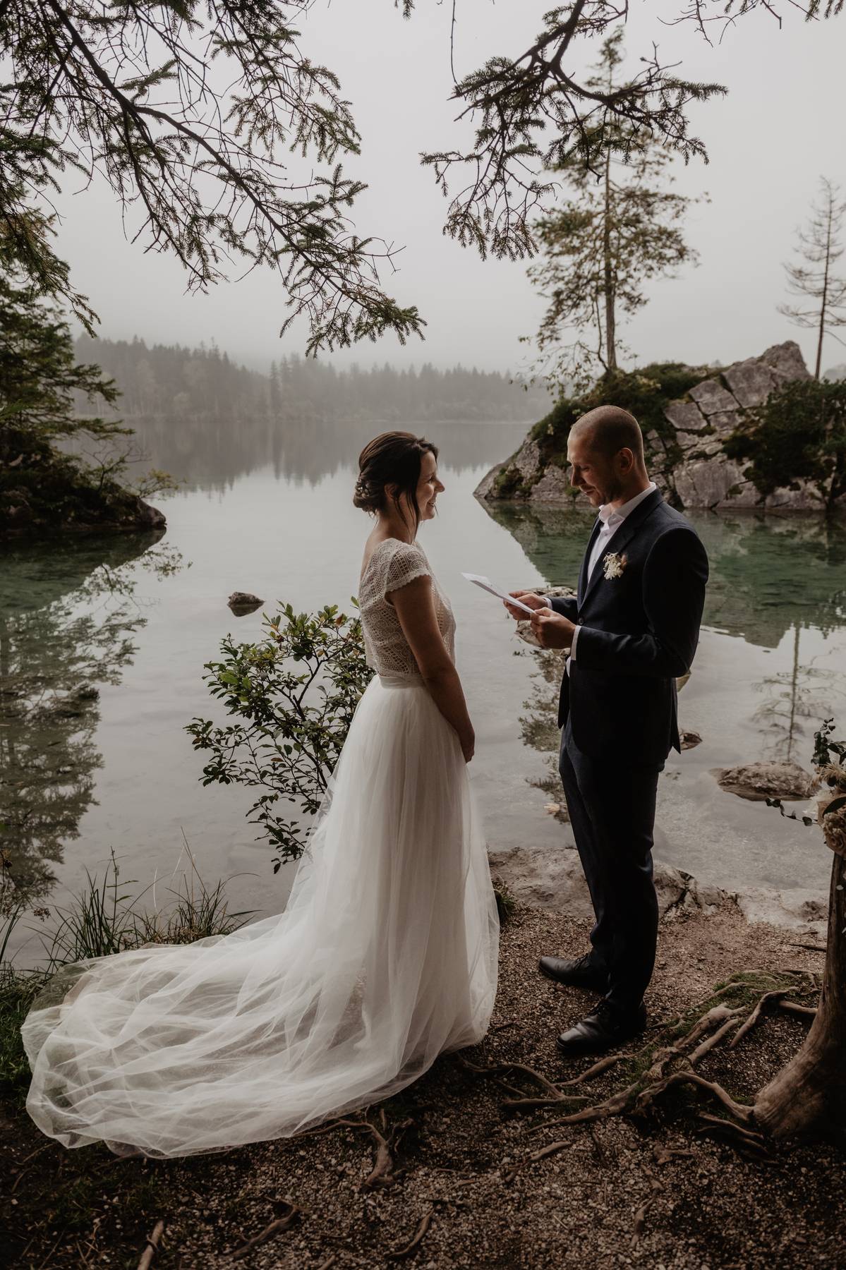 Intimate elopement vows by a calm mountain lake, groom reading while partner listens