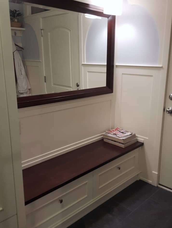 Foyer built-in bench with storage drawers and mirror on the wall