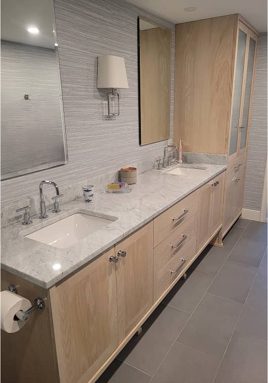Custom bathroom vanity with double sinks, marble countertop and tall storage cabinet in pickled white oak