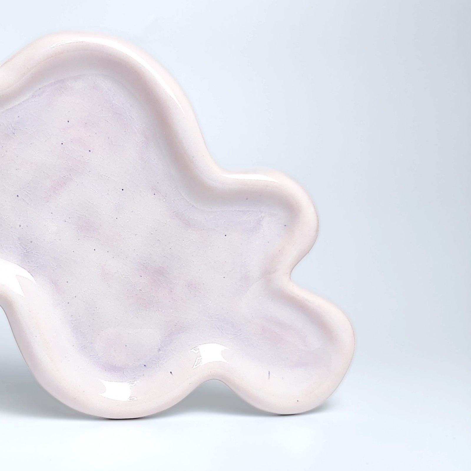 Unique handmade ceramic plate shaped like a cloud, featuring soft pastel pink glazing and an organic sculptural form