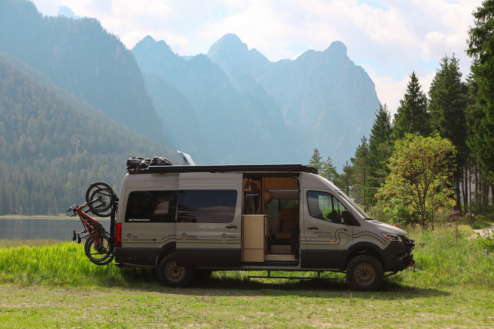 Tiny Planet van parked by a mountain lake